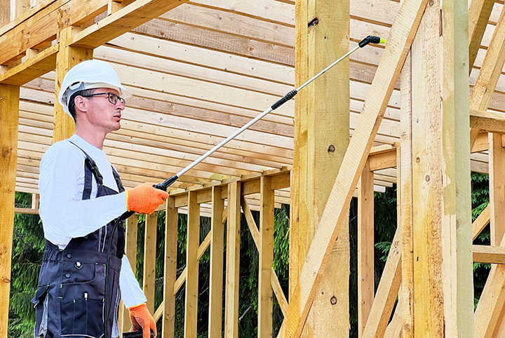 technician spraying a framed building